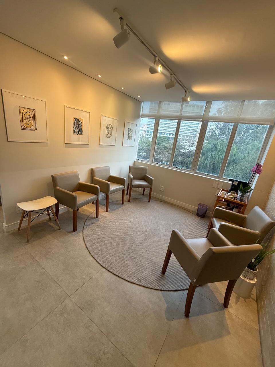 Sala de espera da Goki Geriatria: poltronas confortáveis, quadros da Dra. Sumika na parede, luz natural e vista para o verde